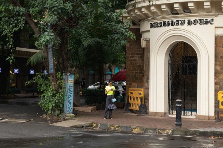 A woman stands in front of a building.