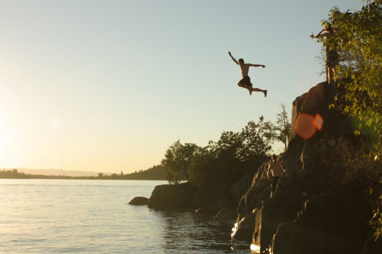 Person leaping from a cliff into the sea at sunset — UPSC Mains essay topic The Cost of Being Wrong Is Less Than the Cost of Doing Nothing