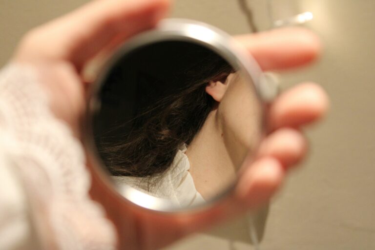 A hand holding a small mirror reflecting a face — visual metaphor for UPSC Mains essay topic Your perception of me is a reflection of you; my reaction to you is an awareness of me.