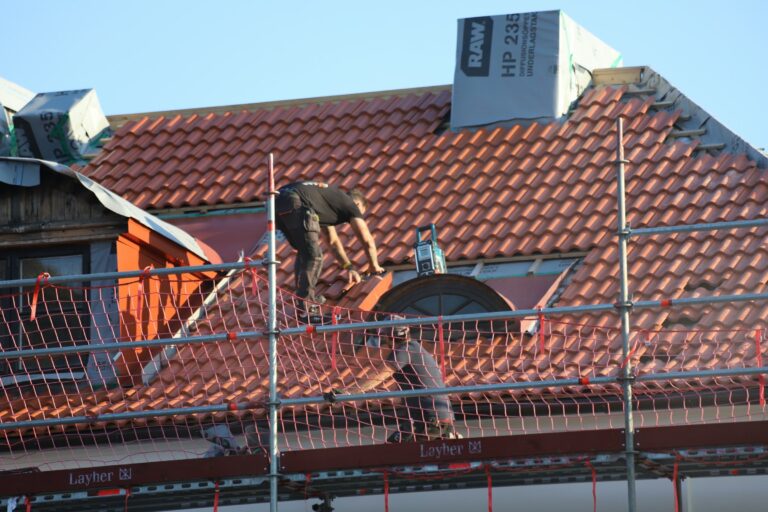 Worker repairing a roof under a clear blue sky — UPSC Mains essay topic The time to repair the roof is when the sun is shining (2022).