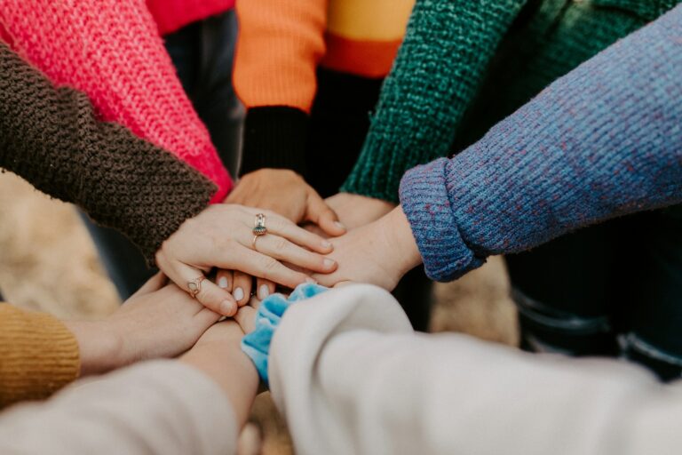 UPSC Mains essay topic The wealth of a nation is the wellbeing of its weakest — hands stacked together in solidarity. Photo by Hannah Busing on Unsplash.