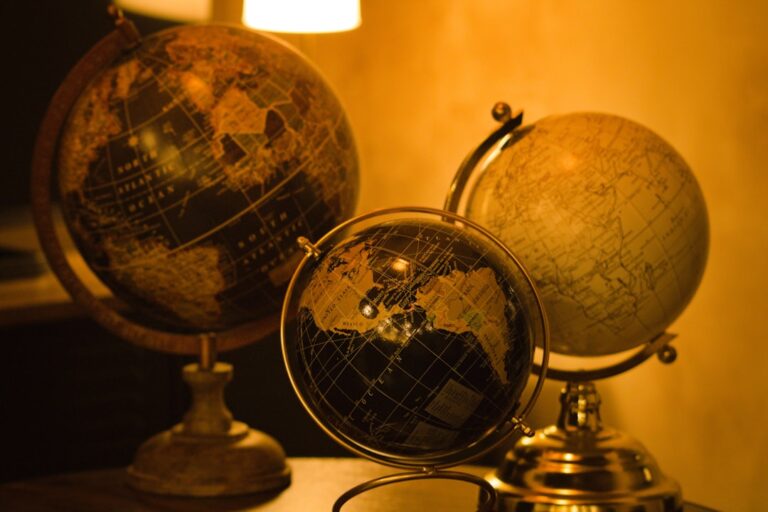 Three antique globes on a study table, representing geography map practice for UPSC preparation.