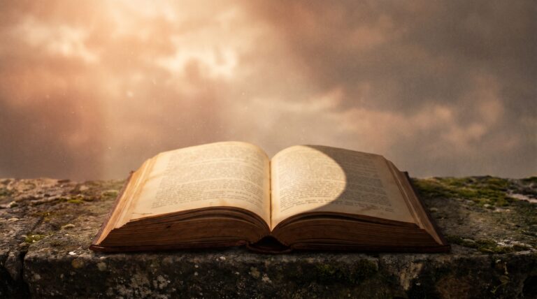 A shadow falling across half an open book on a stone surface