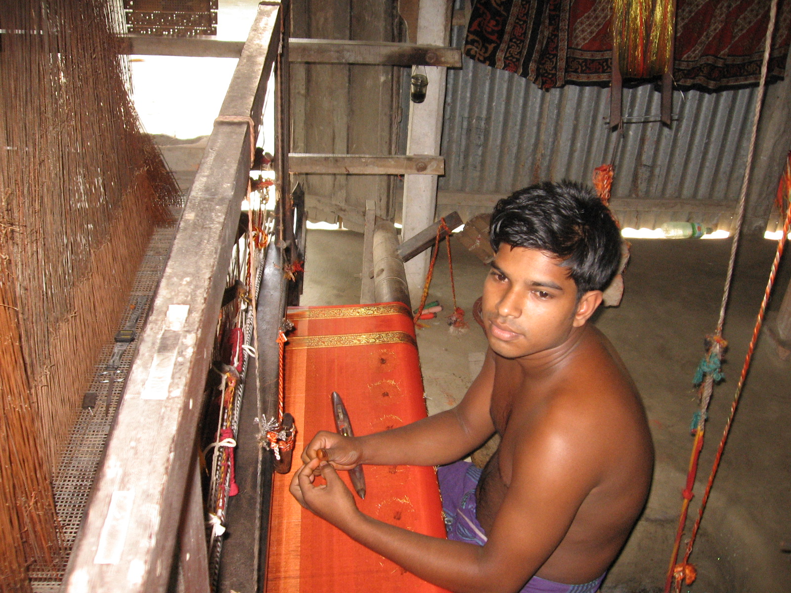 A weaver working on a traditional handloom with colourful yarn