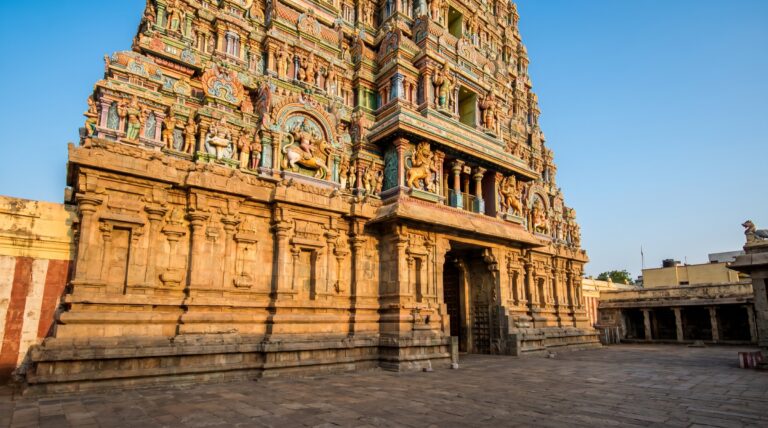 A towering Dravidian gopuram covered in sculpted figures against a blue sky