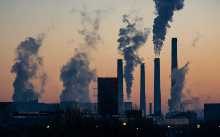 Industrial stacks releasing emissions into a grey sky