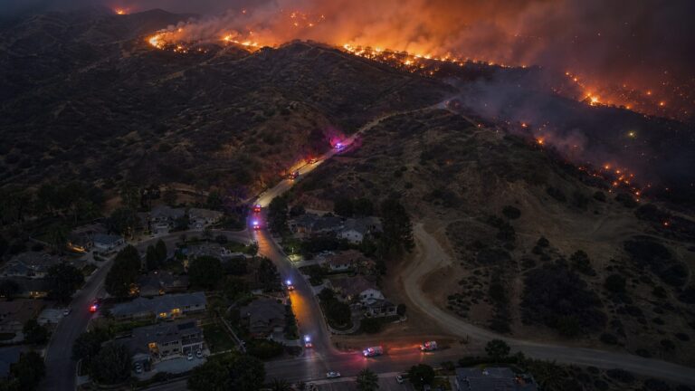 Wind-driven wildfire approaching homes at a wildland-urban interface