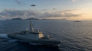 Naval vessels and surveillance aircraft across open western Pacific waters near an island chain