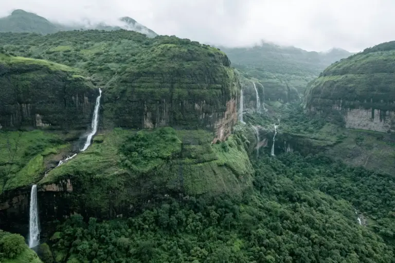 A high waterfall dropping through forested gorge cliffs