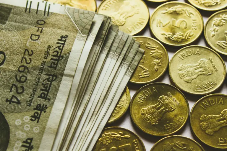 A fanned stack of Indian 500-rupee notes beside gold-colored five-rupee coins