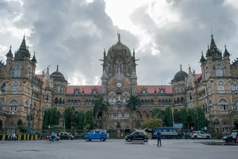 The Gothic stone facade of Chhatrapati Shivaji Maharaj Terminus in Mumbai, with its central dome and taxis on the road