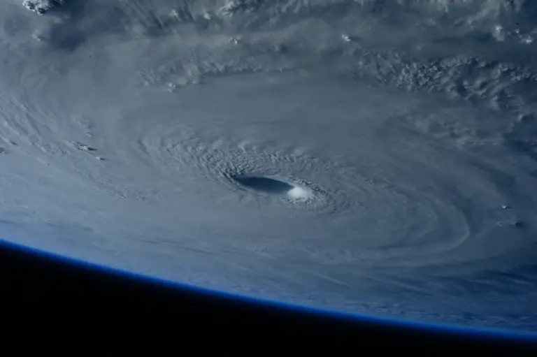 A hurricane seen from orbit, its cloud bands spiralling around a clear central eye