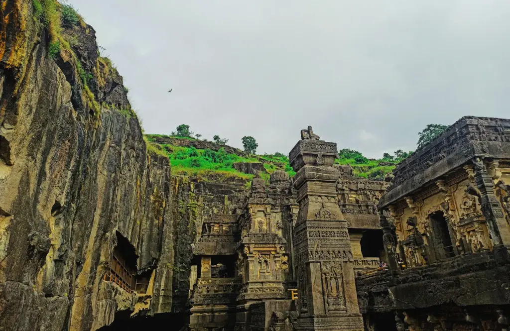 Stone structures at Ellora with a green hill behind them
