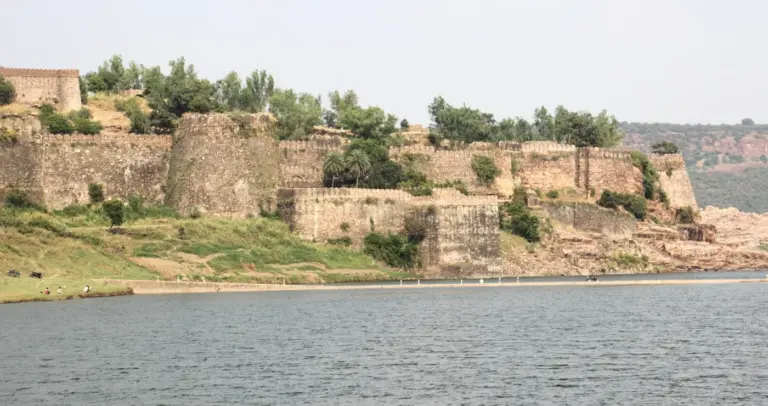 Stone ramparts and bastions of Gagron Fort rising from the riverbank above calm water in Jhalawar, Rajasthan