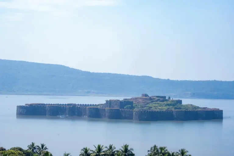 Dark stone walls and rounded bastions of Janjira Fort rising straight out of the Arabian Sea off Murud