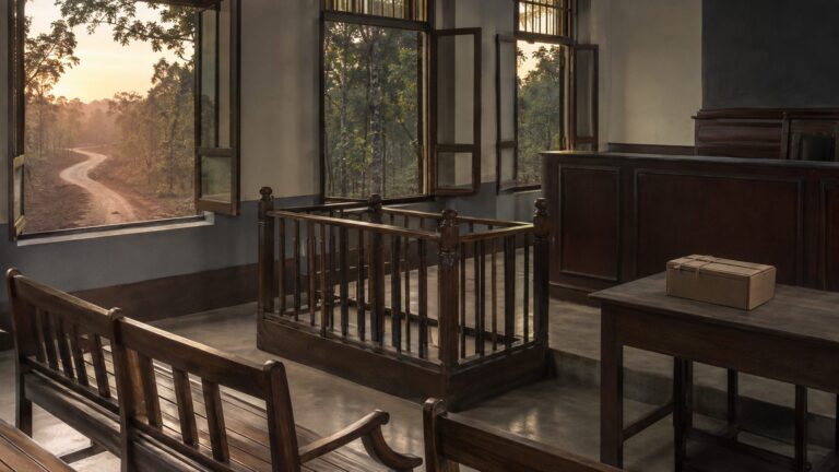 An empty district courtroom overlooking a forest road, representing accountability after the Jhiram Ghati attack