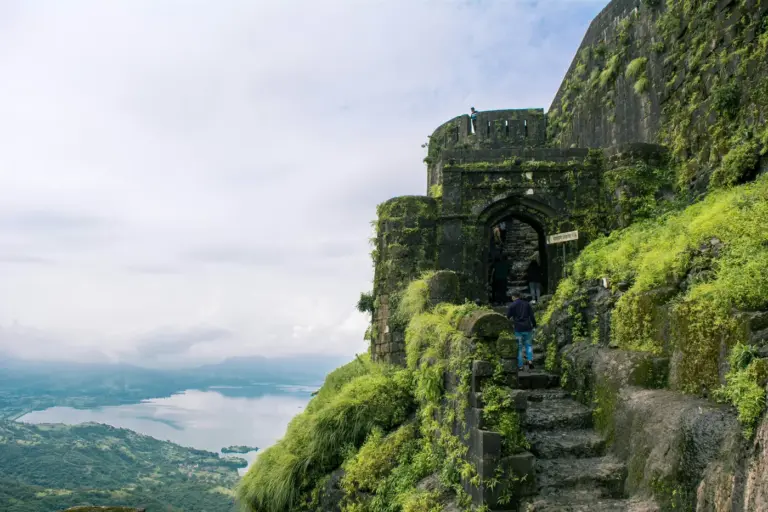 Stone walls of Lohagad Fort running along a green Sahyadri ridge near Lonavala, with the Vinchu Kata spur beyond