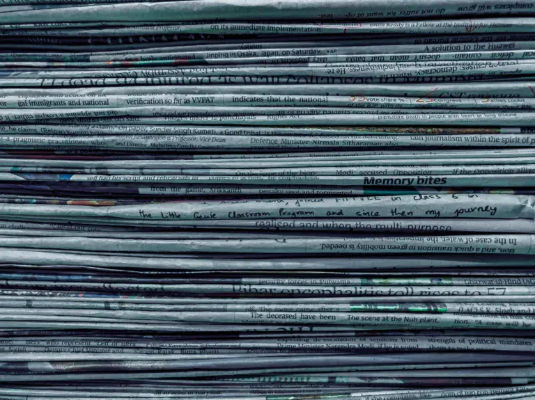 A thick pile of folded newspapers. Photo by Utsav Srestha on Unsplash via Unsplash.