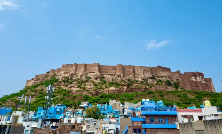 Mehrangarh Fort's sandstone walls rising from a rocky hill above the blue-painted houses of Jodhpur