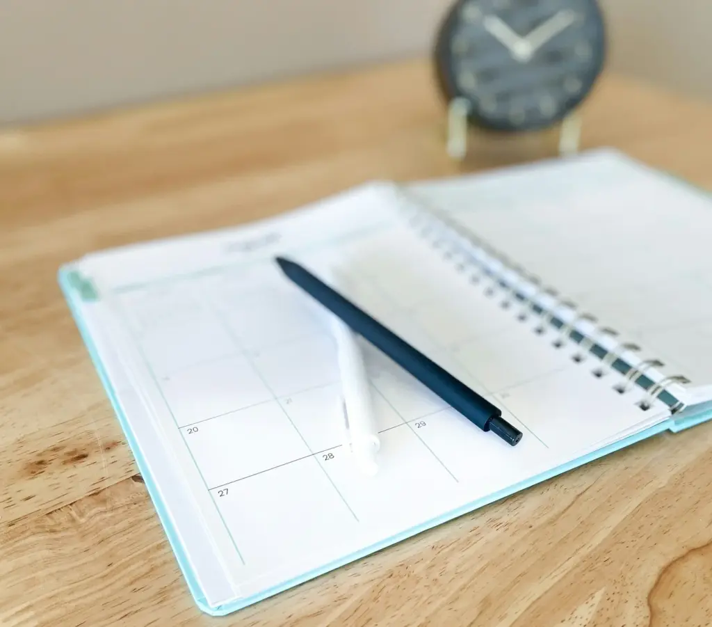 Open planner with a pen on a wooden desk