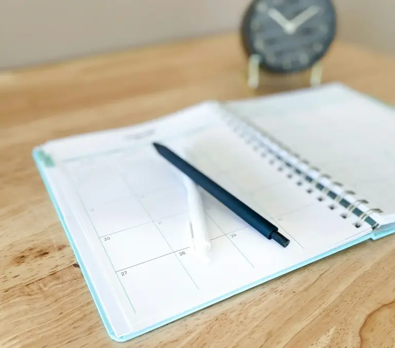 Open planner with a pen on a wooden desk