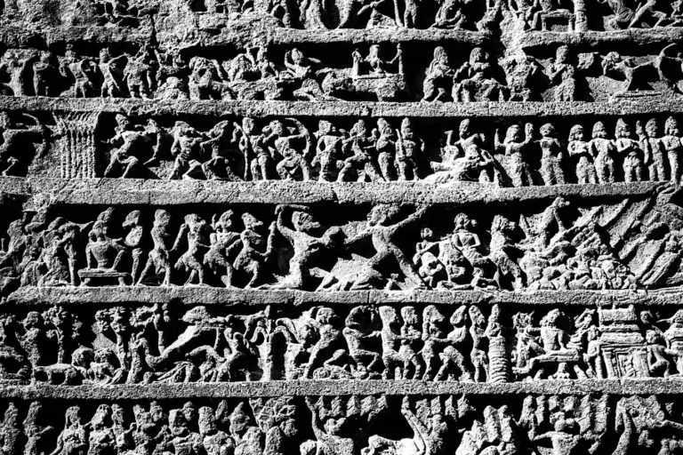 Rows of intricate stone carvings of figures on an ancient temple wall. Photo by Kuldeep Sharma on Unsplash via Unsplash.