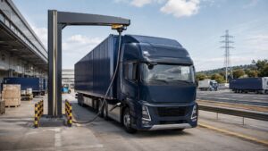 Electric freight truck charging at a logistics hub beside a busy freight corridor