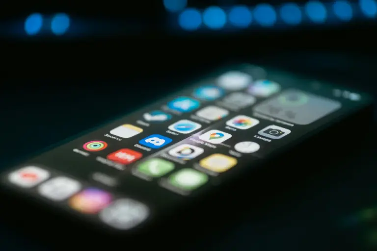 A smartphone home screen full of app icons, shot at an angle in low light with soft focus