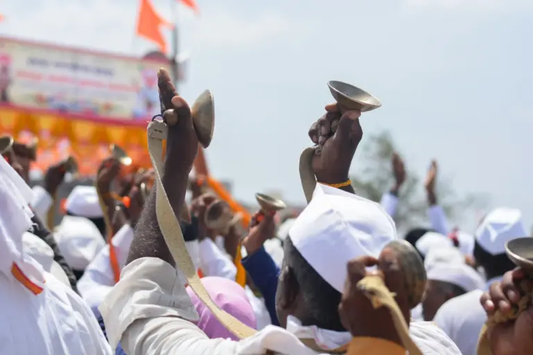 Warkari pilgrims in white caps raise cymbals during the Pandharpur wari procession in Maharashtra