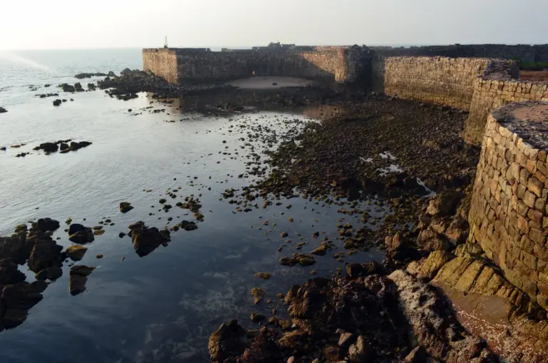 Sindhudurg Fort's stone back wall curving along a rocky Arabian Sea shore off Malvan, Maharashtra