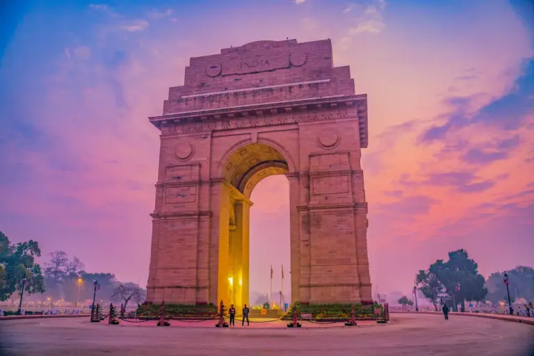 The India Gate war memorial in New Delhi under a pink evening sky. Photo by shalender kumar on Unsplash via Unsplash.