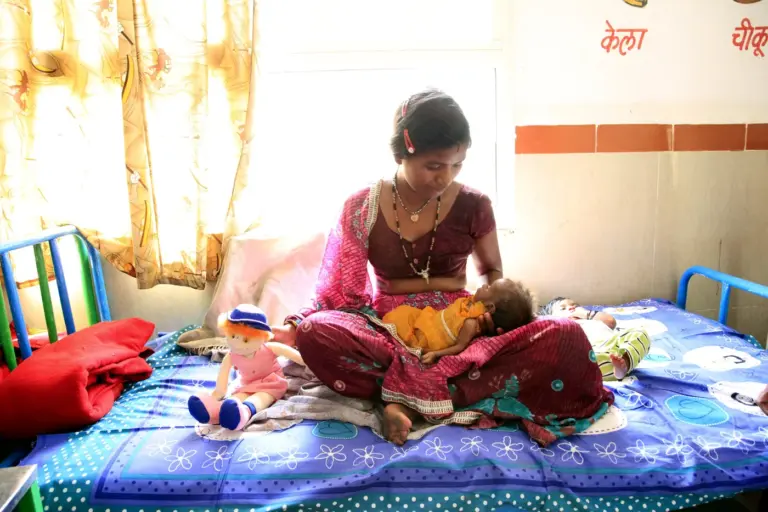 A mother cradles her two-month-old daughter on a bed at a nutrition rehabilitation centre in Madhya Pradesh.