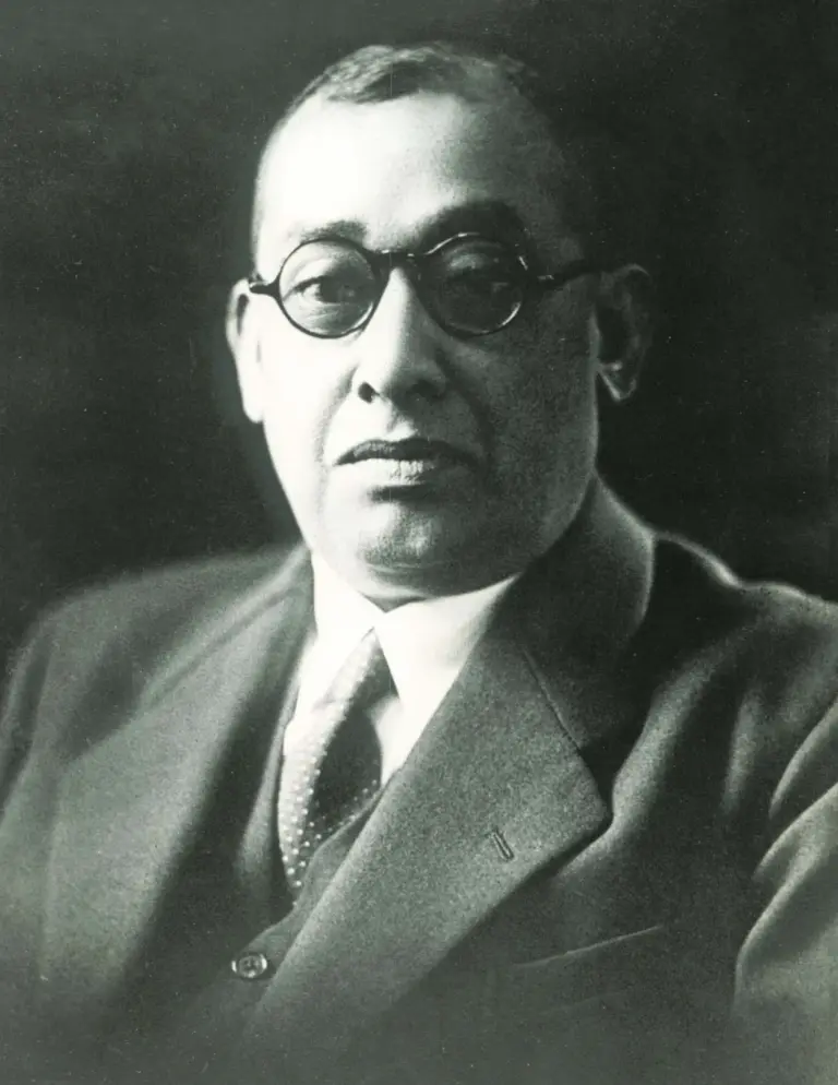 Black and white portrait photograph of Rash Behari Bose wearing round spectacles, a suit and a tie.