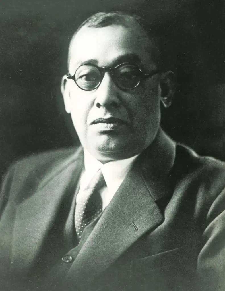 Black and white portrait photograph of Rash Behari Bose wearing round spectacles, a suit and a tie.